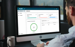 Person viewing the Algo Device Management Platform dashboard on a desktop monitor